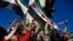 TOPSHOT - Syrian residents in Turkey wave Syrian opposition flags as they celebrate the fall of long-time ruler Bashar al-Assad after rebel fighters took control of the Syrian capital Damascus overnight, in Istanbul on December 8, 2024.