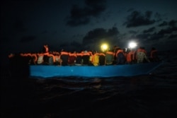 FILE - Dozens of African migrants wait to be assisted by a team of aid workers of the Spanish NGO Open Arms, after spending more than 20 hours at sea, in the Central Mediterranean Sea, Sept. 8, 2020.