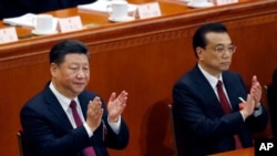 Chinese President Xi Jinping, left, and Chinese Premier Li Keqiang applaud during the opening session of the annual National People's Congress at the Great Hall of the People in Beijing, March 5, 2018.