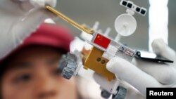 A worker inspects a scale model of the moon rover for China's Chang'e 4 lunar probe, at a factory in Dongguan, Guangdong province, China, Nov. 16, 2018. 