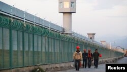 Para pekerja berjalan melintas pagar pembatas dari lokasi yang dikenal sebagai pusat pendidikan kejuruan di Dabancheng di Wilayah Otonomi Xinjiang Uighur, China, 4 September 2018.
