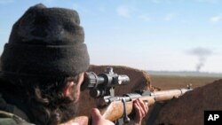 A militant fighter aims a sniper rifle during fighting in Tal Tamr, Hassakeh province, Syria, in this image posted by the Al-Baraka division of the Islamic State group, Feb. 24, 2015.