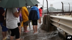 Orang-orang bermain air yang disebabkan oleo Topan Nida di Hongkong Selasa (2/8).