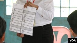 មន្ត្រីរៀបចំការបោះឆ្នោតលើកបង្ហាញសន្លឹកឆ្នោតមួយសន្លឹក​​ បន្ទាប់ពីការិយាល័យ​បោះឆ្នោតនៅទូទាំងប្រទេសបានបិទ នៅឃុំសារិកាកែវ ស្រុកល្វាឯម ខេត្តកណ្តាល ថ្ងៃអាទិត្យ​ ទី២៩ ខែកក្កដា​ ឆ្នាំ២០១៨។ (ស៊ុន ណារិន/VOA)