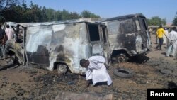 A boy searches the ground next to a burnt-out vehicle, caused by an attack by Boko Haram militants in Bama, Borno State, February 20, 2014.