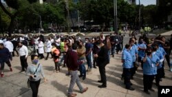 នយោជិត​នានា ចេញ​មក​ឈរ​នៅ​ខាងក្រៅ​អគារ​ធ្វើការ​របស់​ពួកគេ បន្ទាប់ពី​មាន​ការរញ្ជួយដី ដែល​មាន​កម្រិត​ដ៏​ខ្លាំង​មួយ នៅ​ទីក្រុងMexico Cityនៅ​ថ្ងៃអង្គារ​ទី២៣ ខែមិថុនា ឆ្នាំ ២០២០។ (AP)