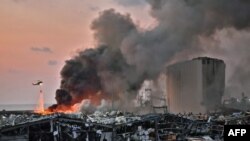 A helicopter puts out a fire at the scene of an explosion at the port of Lebanon's capital Beirut, Aug. 4, 2020. 