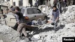 Residents carry an injured woman on a stretcher in a site hit by airstrikes in the rebel-controlled area of Maarat al-Numan town in Idlib province, Syria, Jan. 9, 2016.