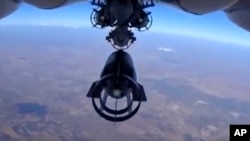 FILE - In this photo made from footage taken from the Russian Defense Ministry website, a bomb is released from a Russian Su-24M jet fighter in Syria, Oct. 5, 2015.