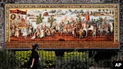 A woman walks past a mural commemorating the meeting of the Spanish conquistador Hernan Cortes and the Aztec Emperor Moctezuma in Mexico City, Tuesday, May 18, 2021. The capital of the Aztec empire, now known as Mexico City, fell after a prolonged siege 5