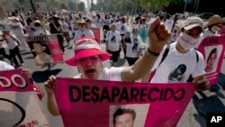 FILE - Mothers, relatives and friends march with banners and posters showing images of relatives that have been disappeared, during Mother's Day, in Mexico City.