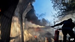 Un résident tente d'éteindre le feu sur le garage d'une église démarré par des habitants manifestants contre le remplacement de la candidat à la mairie, à Atteridgeville, Pretoria, le 21 juin 2016.