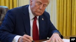 President Donald Trump signs a document in the Oval Office at the White House, Jan. 30, 2025, in Washington. 