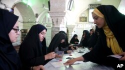 A voter gets ballots to cast in the presidential and municipal council election at a polling station in the city of Qom, 78 miles (125 kilometers) south of the capital Tehran, Iran, May 19, 2017.