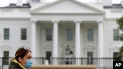 Seorang perempuan berjalan melintasi depan Gedung Putih, Washington, D.C., 1 April 2020. (Foto: dok).