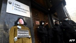 Sebuah manekin yang melambangkan anggota parlemen pro-Rusia dan sekutu Putin Viktor Medvedchuk dengan jaket yang diisi dengan rubel Rusia di luar kantor Jaksa Agung, menuntut hukuman bagi Medvedchuk atas tuduhan pengkhianatan, di Kiev, 25 Maret 2021. (Sergei SUPINSKY/AFP)