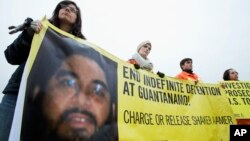 FILE - Human rights activists hold a banner with a picture of Saudi national Guantanamo detainee Shaker Aamer during a rally near the White House in Washington, Jan. 11, 2013.