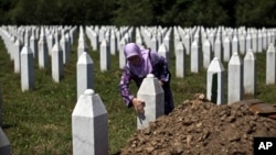 FILE - A woman touches the tombstone of a relative at the Potocari, memorial complex near Srebrenica, 150 kilometers northeast of Sarajevo, Bosnia, July 10, 2015. 