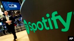 FILE - A trading post sports the Spotify logo on the floor of the New York Stock Exchange, April 3, 2018.