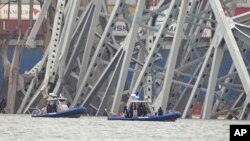 Kapal milik polisi bergerak di dekat kapal kargo yang terjebak di struktur jembatan Francis Scott Key di Baltimore, Maryland, pada 27 Maret 2024. (Foto: AP/Steve Helber)