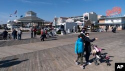People enjoy the boardwalk, Friday, Nov. 13, 2020, in Rehoboth Beach, Del. This resort town known for Atlantic waves that are sometimes surfable, fresh-cut French fries and a 1-mile wooden boardwalk that dates back to the 1870s. (AP Photo/Alex Brandon)