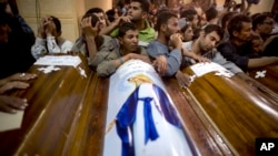 FILE - Relatives of Coptic Christians who were killed during a bus attack, surround their coffins, during their funeral service, at Abu Garnous Cathedral in Minya, Egypt, May 17, 2017. The Libya connection in the Manchester concert bombing and Friday’s attack on Christians in Egypt has shone a light on the threat posed by militant Islamic groups that have taken advantage of lawlessness in the troubled North African nation to put down roots, recruit fighters and export jihadists to cause death and carnage elsewhere. 