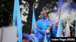 Para buruh merayakan "kemenangan" mereka setelah hakim di Mahkamah Konstitusi membacakan putusan uji materi UU Cipta Kerja agar ditinjau ulang oleh DPR dan Pemerintah Indonesia, Jakarta, 25 November 2021. (Foto: Indra Yoga/VOA)