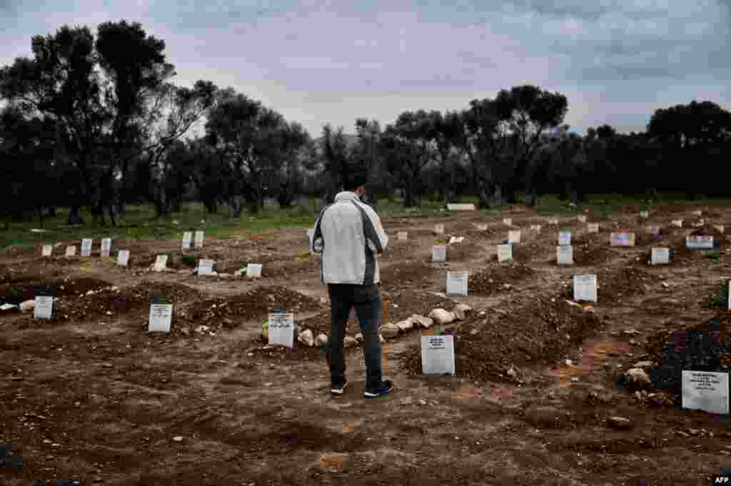 A man looks at the graves in Mytilene, Greece, at a graveyard for refugees and migrants who drowned in their attempt to cross the Aegean sea from Turkey to the island of Lesbos.