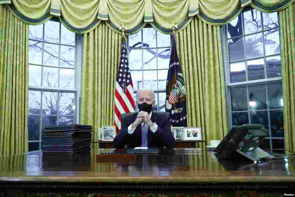 U.S. President Joe Biden signs executive orders in the Oval Office of the White House in Washington, after his inauguration as the 46th President of the United States, U.S., January 20, 2021. REUTERS/Tom Brenner