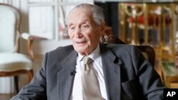 In this photo taken on Thursday, March 19, 2015, former U.S. Ambassador to Cambodia John Gunther Dean holds the American flag he carried when he was evacuated from the U.S. Embassy in Cambodia during an interview with the Associated Press in Paris, France.