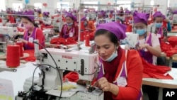 Garment workers sew clothes in a factory as they wait for visit by Prime Minister Hun Sen outside of Phnom Penh, Cambodia, Wednesday, Aug. 30, 2017. 