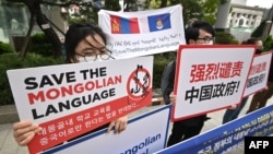 FILE - People hold placards reading "Save the Mongolian language" during a rally denouncing China’s plan to introduce Mandarin-only classes at schools in Inner Mongolia, a semi-autonomous region in China, on a street near the Chinese Embassy in Seoul, South Korea, Sept. 24, 2020.