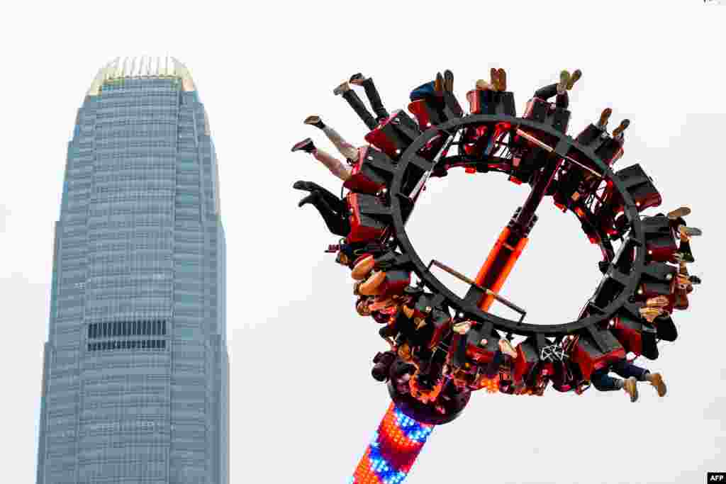 People ride a Luna Park&#39;s Sledgehammer in front of the International Financial Centre (IFC) tower in Hong Kong.
