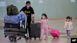 Passengers wear face masks after arriving at Hong Kong airport, Monday, March 23, 2020. Hong Kong will close its border to non-residents for 14 days starting from Wednesday, its chief executive announced on Monday after the number of coronavirus patients 