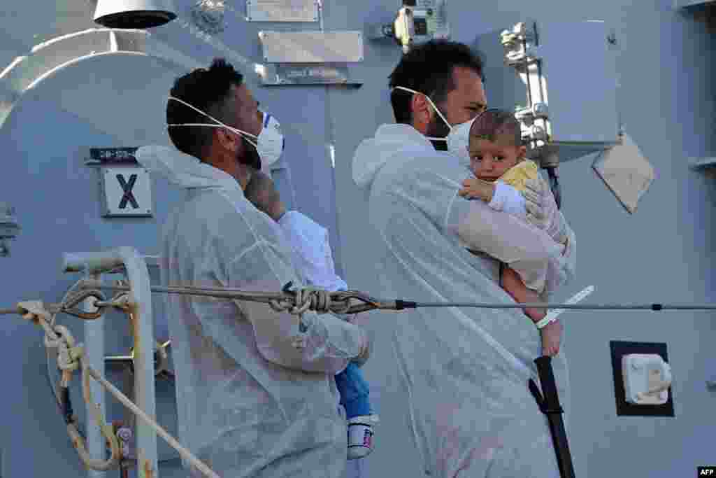 Rescuers holds babies as the Italian military ship &quot;Chimera&quot; - with around 350 would-be immigrants onboard - arrives in the port of Pozzallo, Sicily, one day after a rescue operation off the coast of Sicily.