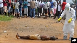 A health worker sprays disinfectant on the body of a man suspected of dying of Ebola in Monrovia, Liberia.