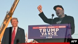 (FILES) Tesla CEO Elon Musk (R) speaks on stage as he joins former US President and Republican presidential candidate Donald Trump during a campaign rally at site of his first assassination attempt in Butler, Pennsylvania on October 5, 2024.