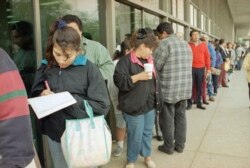 FILE - A Salvadoran woman fills in her application for a green card while waiting in line outside an immigration office in Los Angeles.