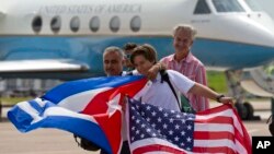 FILE - Passengers of JetBlue Flight 387 holding U.S. and Cuban flags pose for photos in front of the plane transporting U.S. Transportation Secretary Anthony Foxx, at the airport in Santa Clara, Cuba, Aug. 31, 2016.