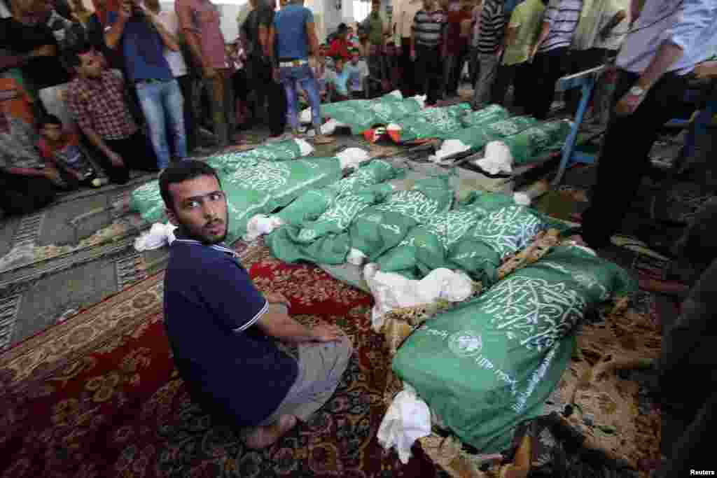 A man sits next to the bodies of Palestinians from the Abu Jama&#39;e family, who medics said were killed in an Israeli air strike that destroyed their house, during their funeral at a mosque, in Khan Younis, in the southern Gaza Strip, July 21, 2014.
