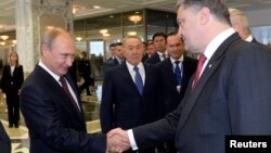 Russian President Vladimir Putin (L) shakes hands with his Ukrainian counterpart Petro Poroshenko at the start of talks in Minsk, Belarus, Aug. 26, 2014.