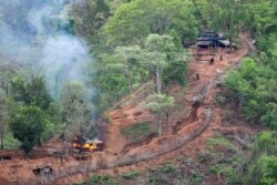 FILE - Ethnic minority Karen troops are seen after setting fire to a building at a Myanmar army outpost near the Thai border, seen from the Thai side along the Thanlwin River in Mae Hong Son province, Thailand, April 28, 2021.