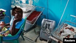 FILE - A woman holds her newborn baby in a nursery, while a newborn nearby is attached to a ventilator at Juba Teaching Hospital in Juba, April 3, 2013. South Sudan has one of the highest maternal mortality rates in the world.
