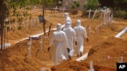 FILE - Health workers walk inside a new graveyard as they move bury people suspected of dying from the Ebola virus on the outskirts of Monrovia, Liberia, March 11, 2015. 