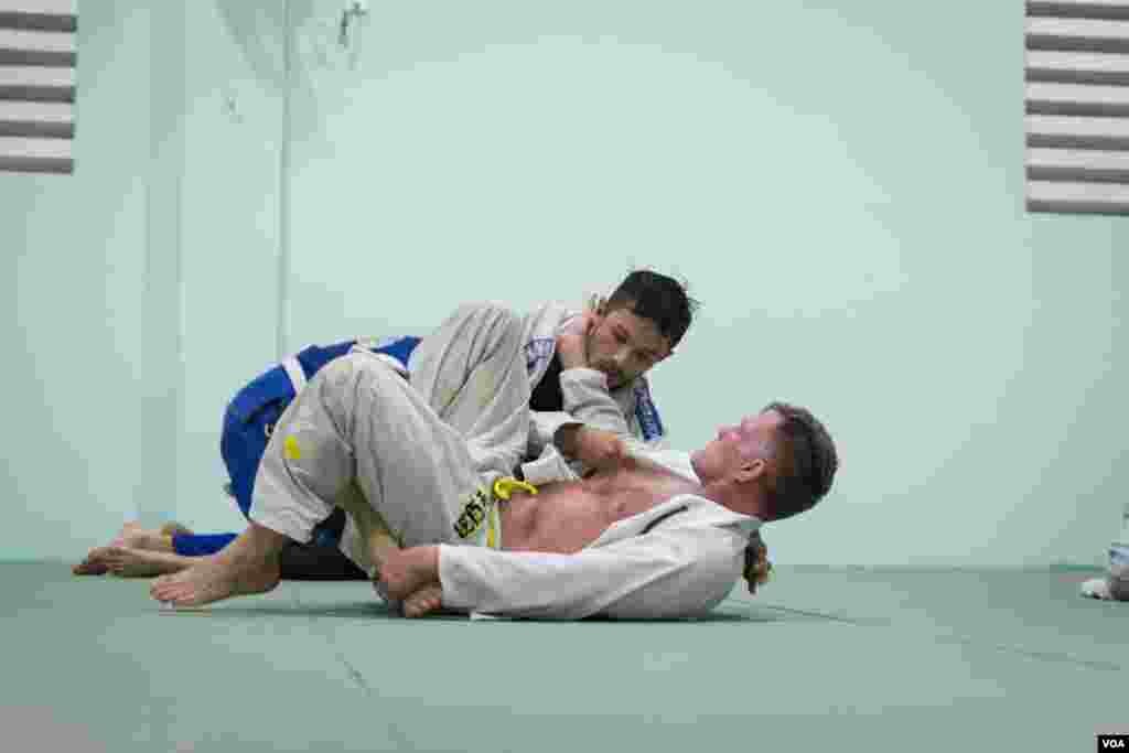 One of the well-known BJJ trainers, Chris Haueter (below) and Vivaddhana Khaou (in white Kimono), a head instructor at Brazilian Jiu-Jitsu Cambodia, have a short matches following a training at the Olympic Stadium, in Phnom Penh, on February 22, 2016. (Neou Vannarin/VOA Khmer)