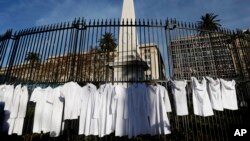 FILE - White medical coats hanging from the iron gate that surrounds the national monument May Pyramid, as a symbolic act against efforts to legalize abortion, in Buenos Aires, Argentina, July 15, 2018.