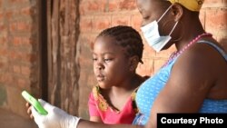 Une élève travaille avec sa mère sur un cours à l'aide d'une tablette fournie par l'organisation caritative britannique Voluntary Services Overseas, au Malawi. (VSO / Craig Mawanga)