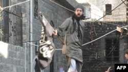 A handout image released by the Syrian opposition's Shaam News Network allegedly shows a Syrian opposition activist waving an black flag of the Islamist Jihadists who are accused of recruiting children. 