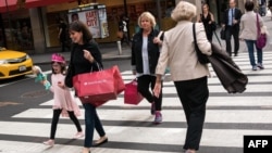 FILE - People carrying shopping bags walk along Fifth Avenue, Sept. 27, 2016 in New York City. 