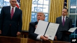 Predsednik Donald Tramp, u prisustvu potpredsednika Majka Pensa i šefa kabineta Rajnsa Pribusa, pokazuje uredbu o povlačenju SAD iz TPP-a